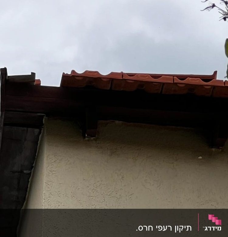 גג רעפים אדומים על מבנה עם קיר בהיר